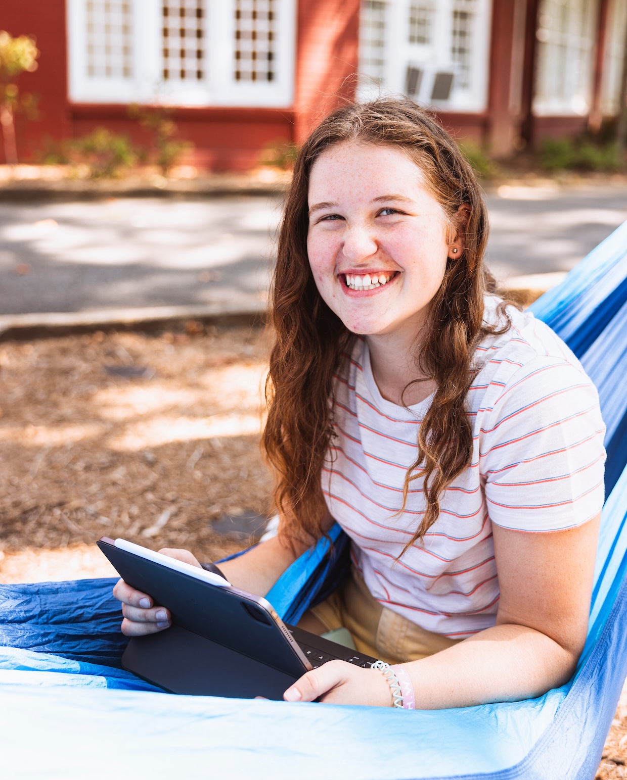 Student studying homework in hammock.