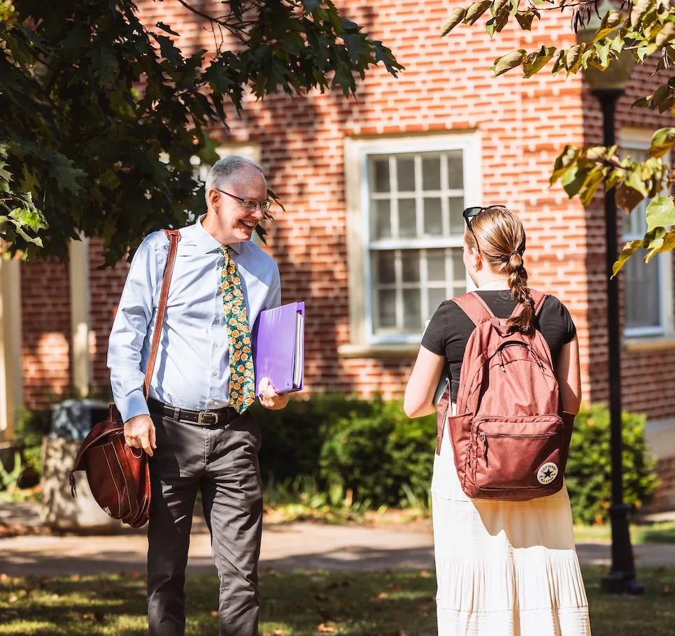 Student speaking with professor on campus.