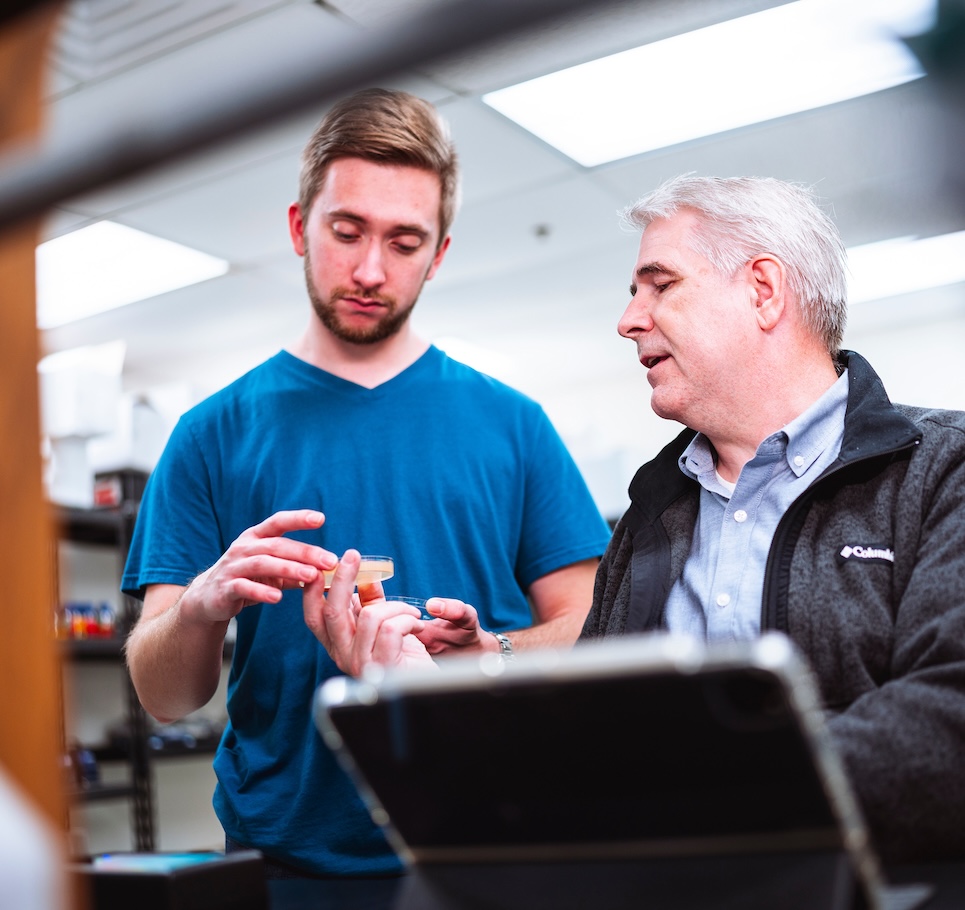 Chemistry professor handing student a Petri dish