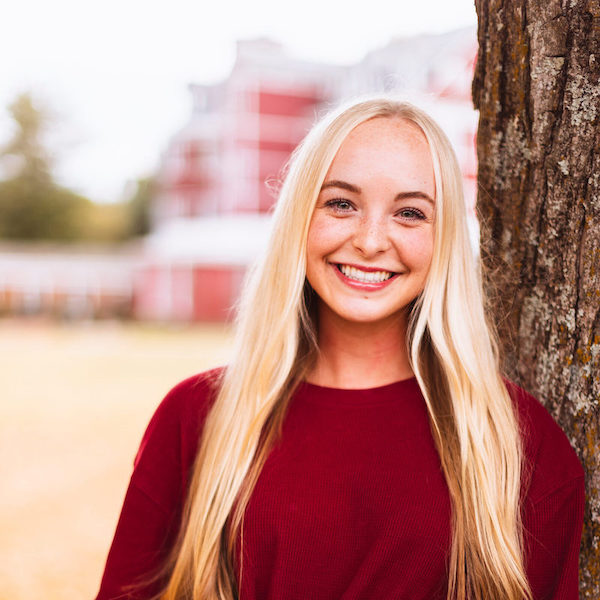 Female Southern Virginia University student smiling while standing by a tree